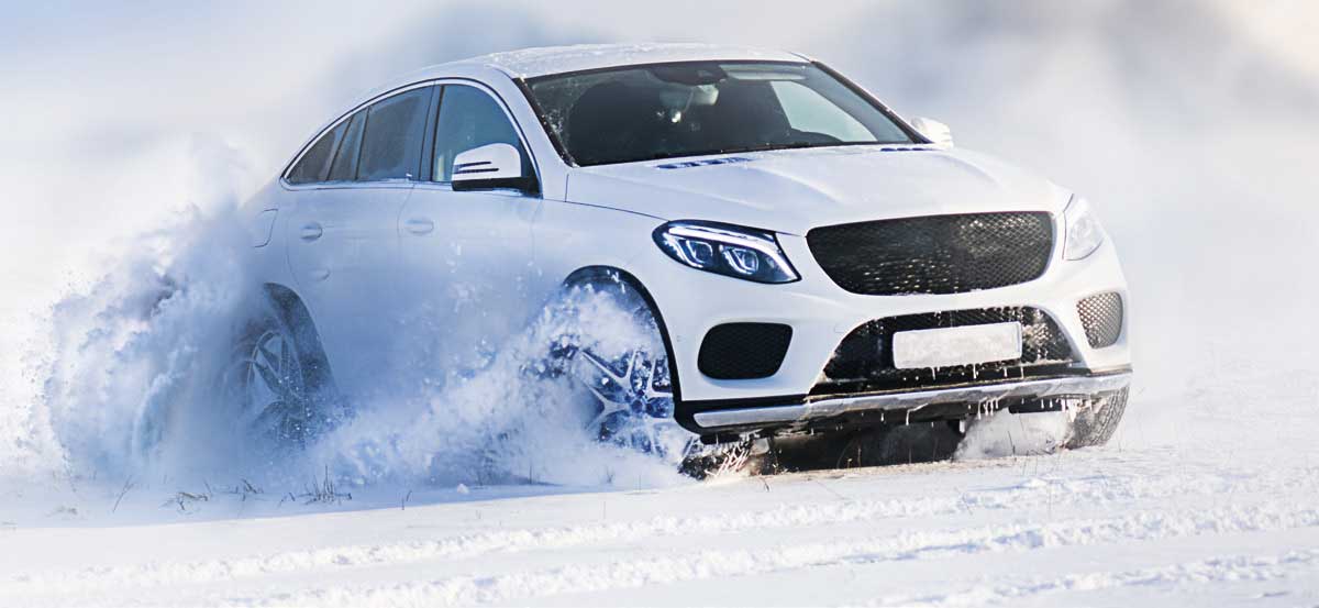 Aufnahme eines weissen Autos, das auf beschneitem Felde sportlich aktiv fährt.
